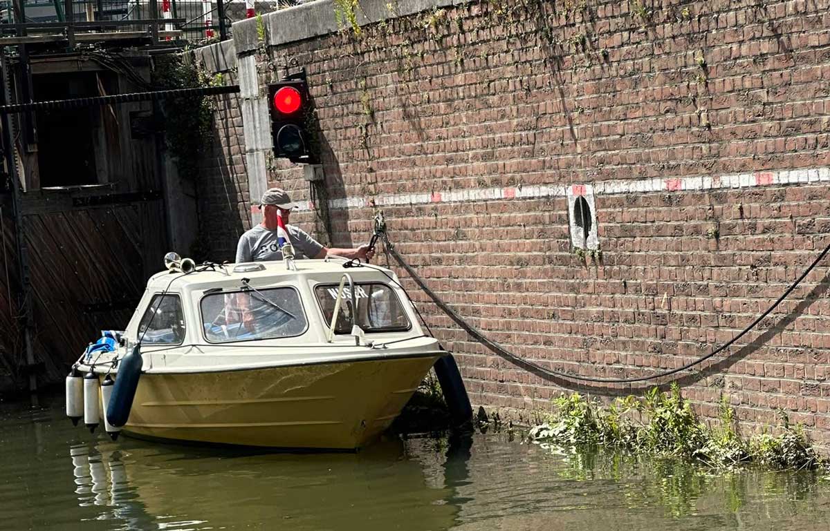 Poul Jørgensen står i den lilla motorbåten Nuser i en sluss.
